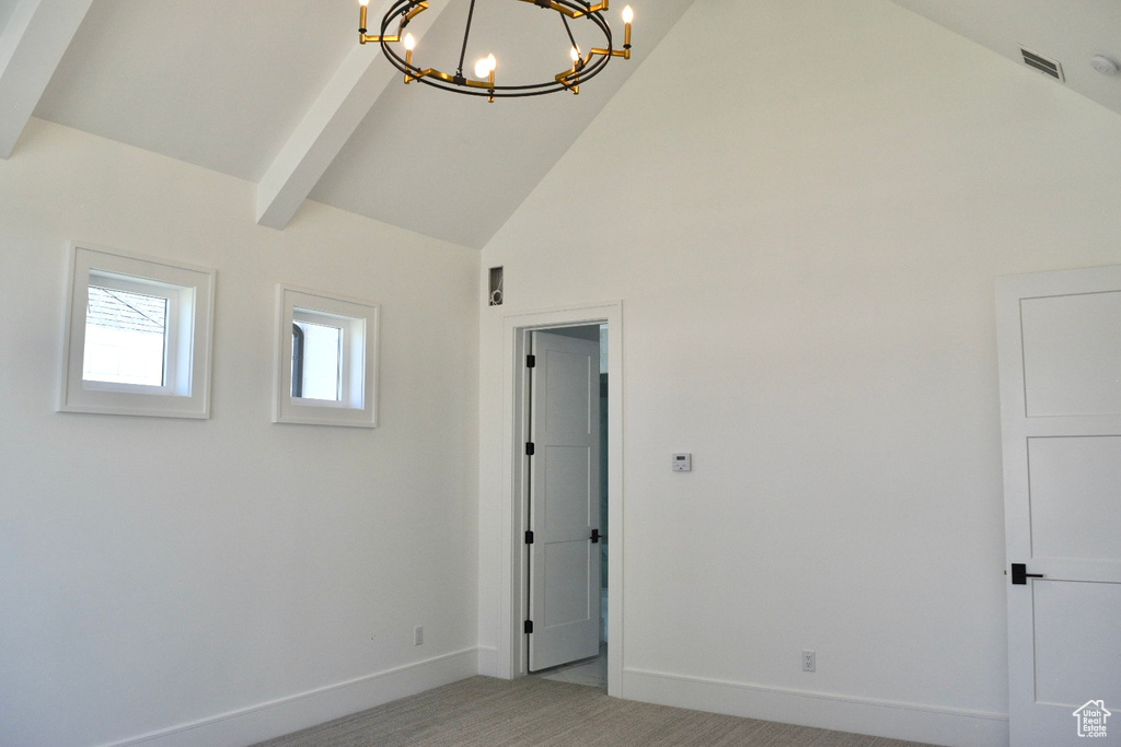 Unfurnished room with carpet, vaulted ceiling with beams, and an inviting chandelier