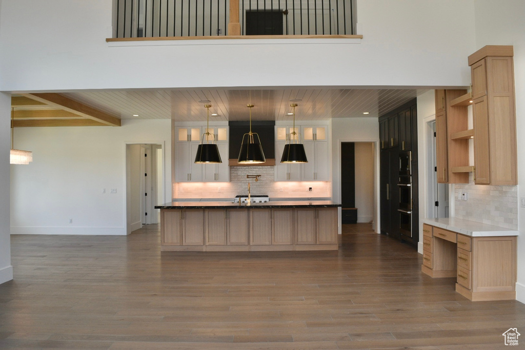 Kitchen with a kitchen island with sink, light brown cabinets, and tasteful backsplash