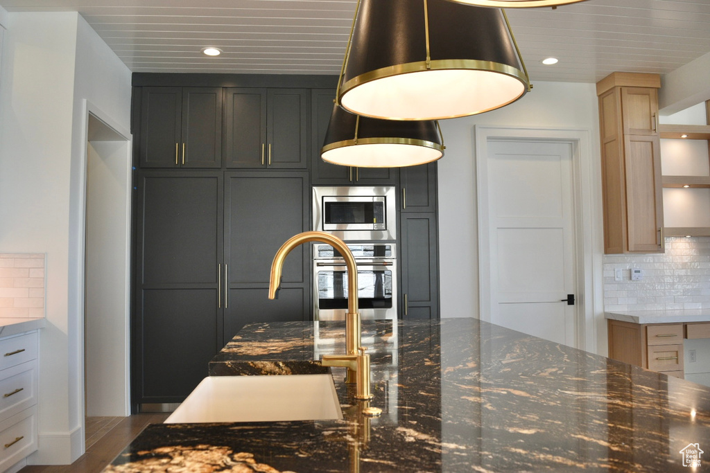 Kitchen featuring dark stone countertops, tasteful backsplash, stainless steel appliances, and hardwood / wood-style flooring