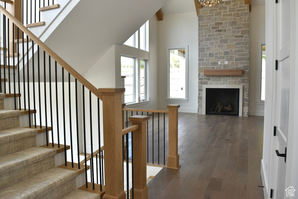 Staircase featuring brick wall, dark hardwood / wood-style flooring, a fireplace, and a towering ceiling