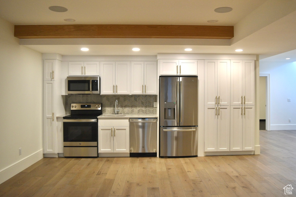 Kitchen featuring sink, appliances with stainless steel finishes, white cabinets, and light hardwood / wood-style floors