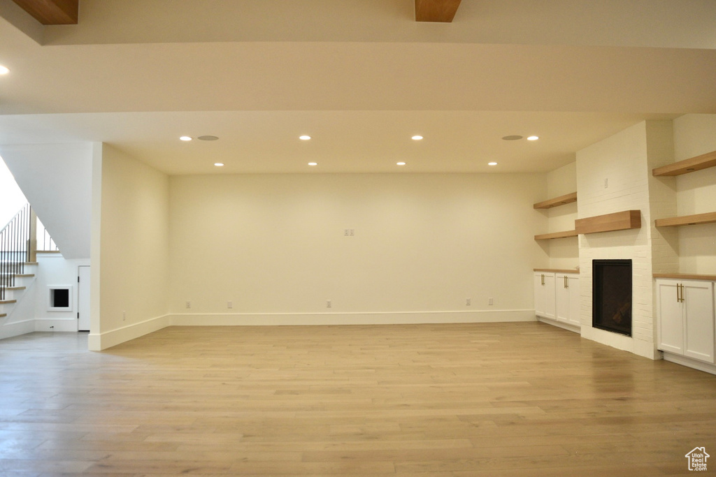 Unfurnished living room featuring light hardwood / wood-style floors and a large fireplace