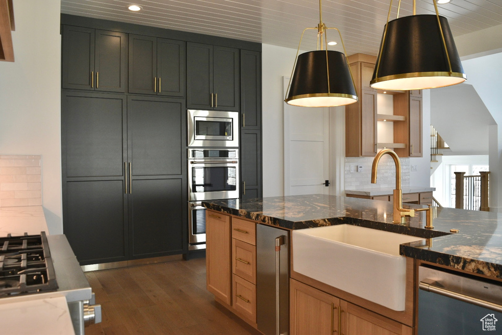 Kitchen featuring decorative backsplash, stainless steel appliances, dark stone countertops, and sink