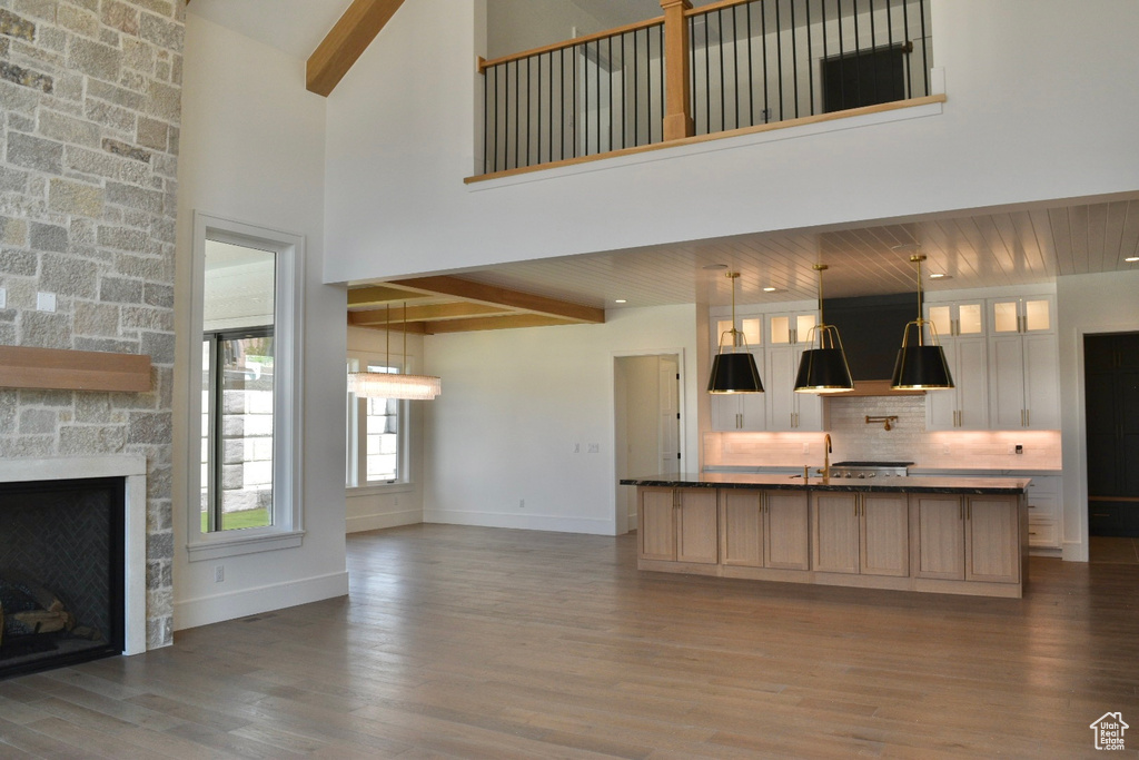 Unfurnished living room with wood-type flooring, a fireplace, and a towering ceiling