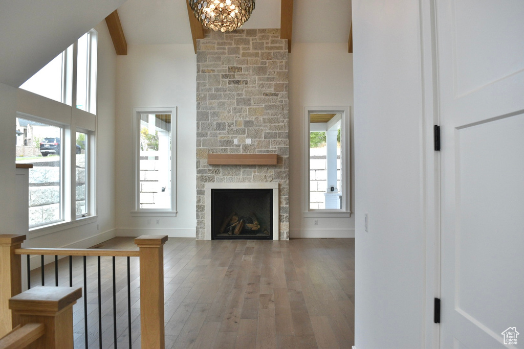 Unfurnished living room with beamed ceiling, a stone fireplace, hardwood / wood-style flooring, and plenty of natural light