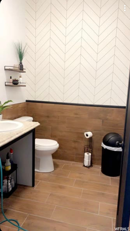Bathroom with vanity, toilet, and tile walls