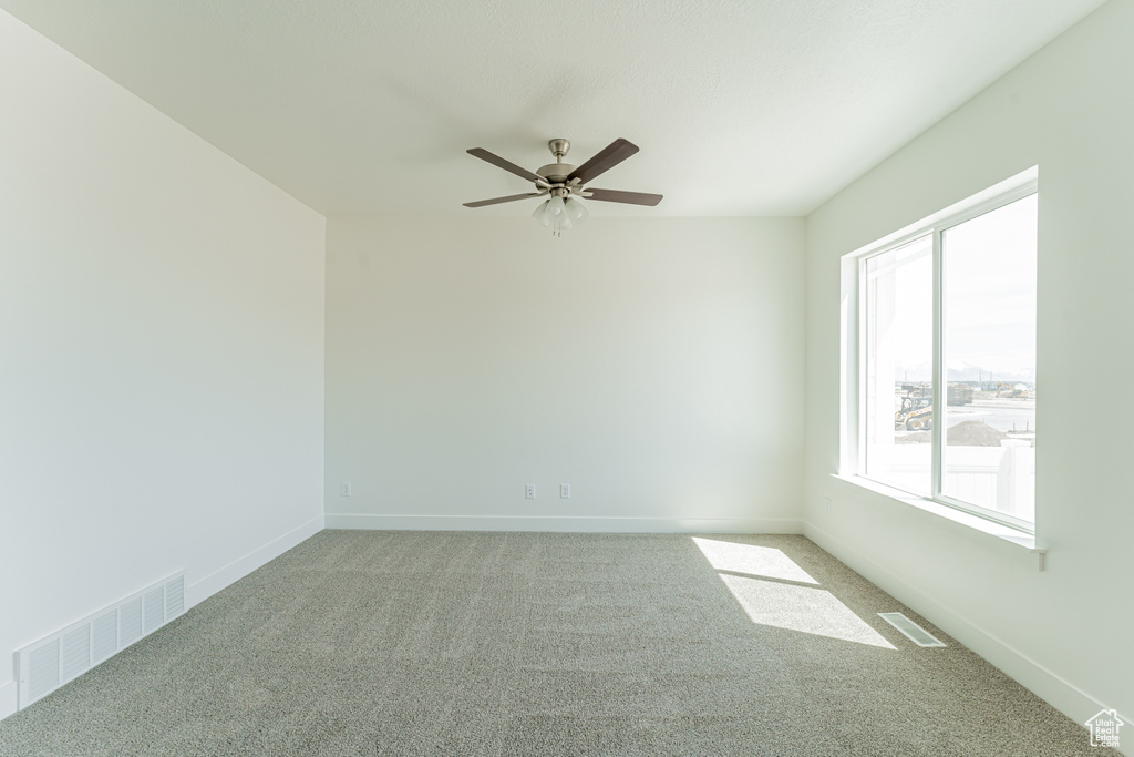 Empty room with ceiling fan, carpet, and a wealth of natural light