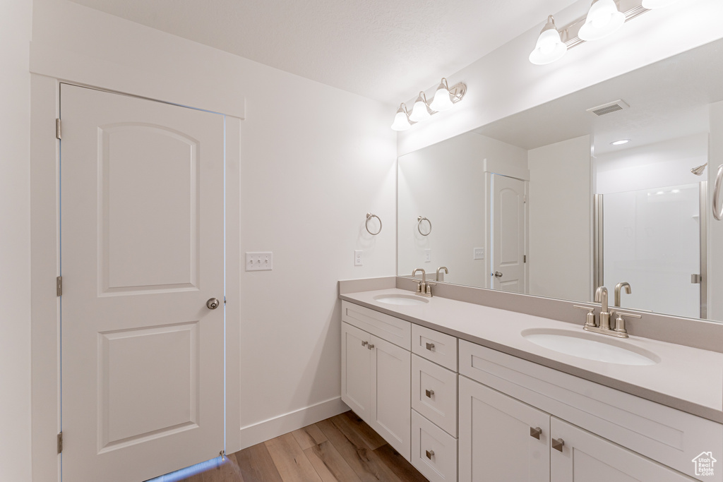 Bathroom featuring hardwood / wood-style floors, oversized vanity, and dual sinks