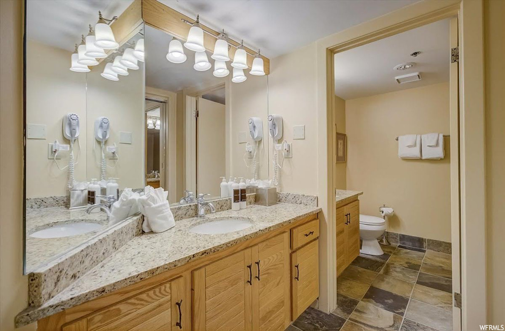 Bathroom with toilet, tile flooring, and dual vanity