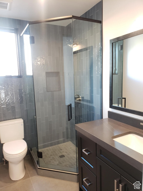 Bathroom featuring tile patterned flooring, a shower with door, toilet, and vanity