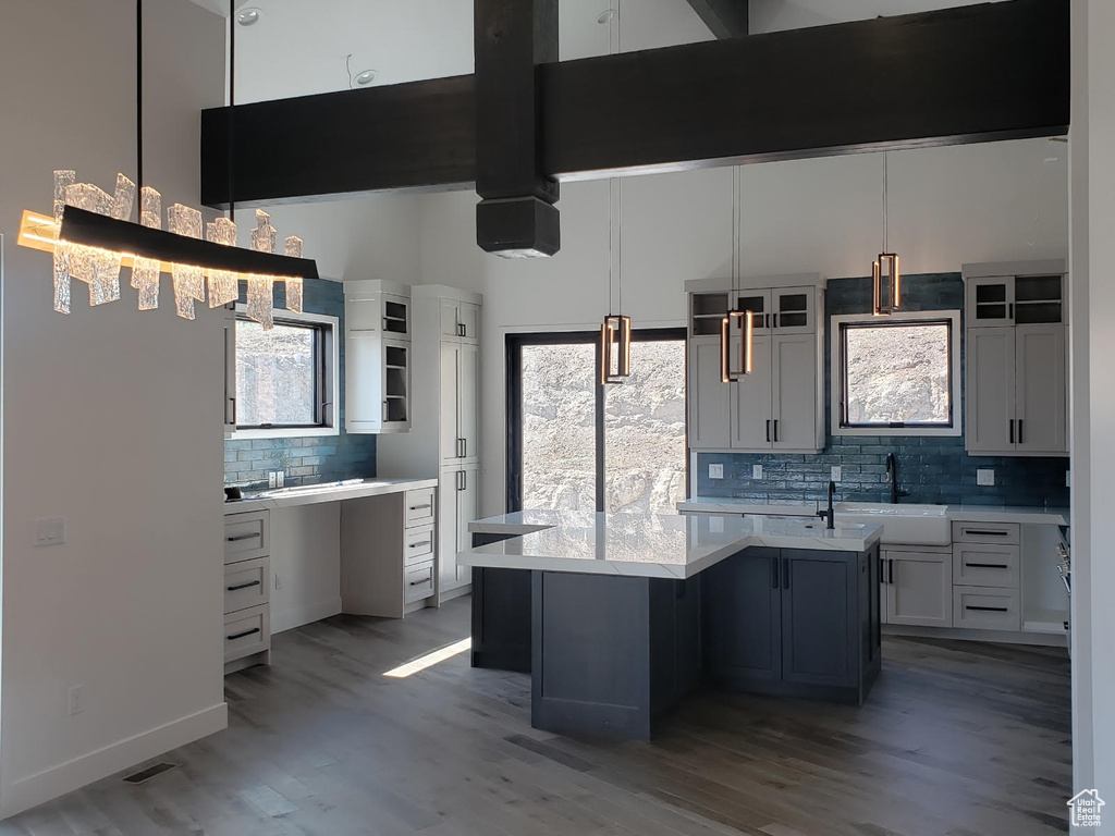 Kitchen with sink, hanging light fixtures, backsplash, a center island, and hardwood / wood-style flooring