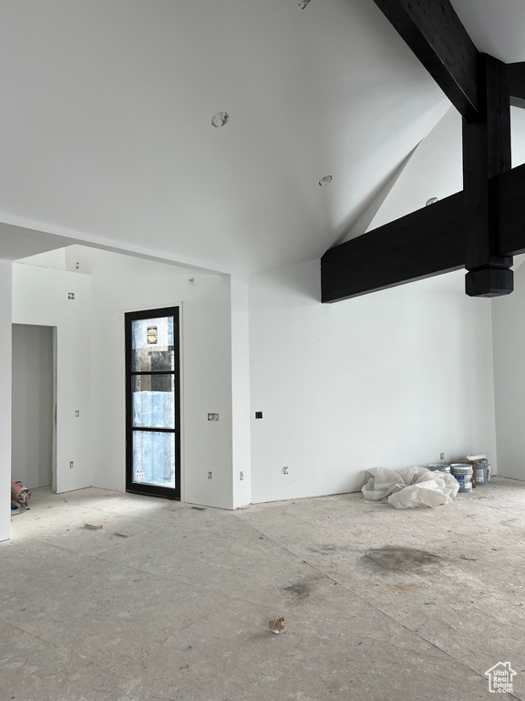 Empty room with lofted ceiling with beams