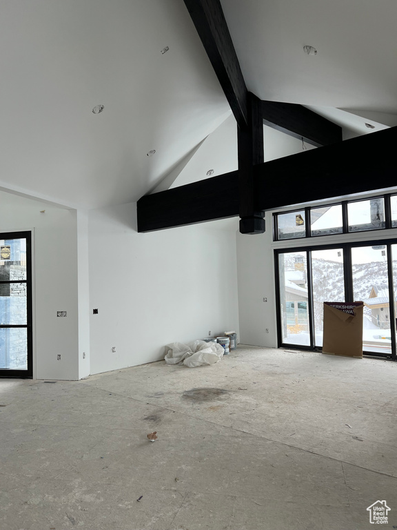 Unfurnished room with high vaulted ceiling, plenty of natural light, and beam ceiling
