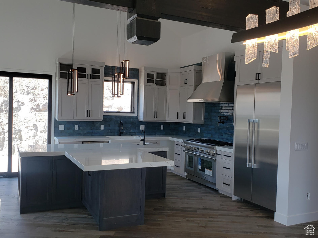 Kitchen with tasteful backsplash, a kitchen island, wall chimney exhaust hood, wood-type flooring, and high end appliances