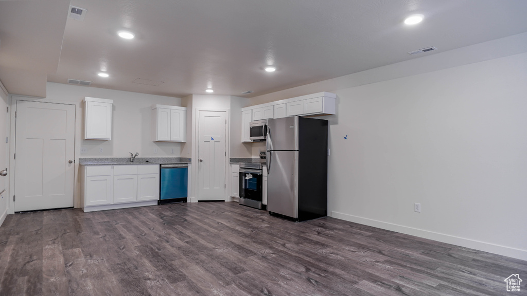 Kitchen with white cabinets, dark hardwood / wood-style floors, appliances with stainless steel finishes, and sink