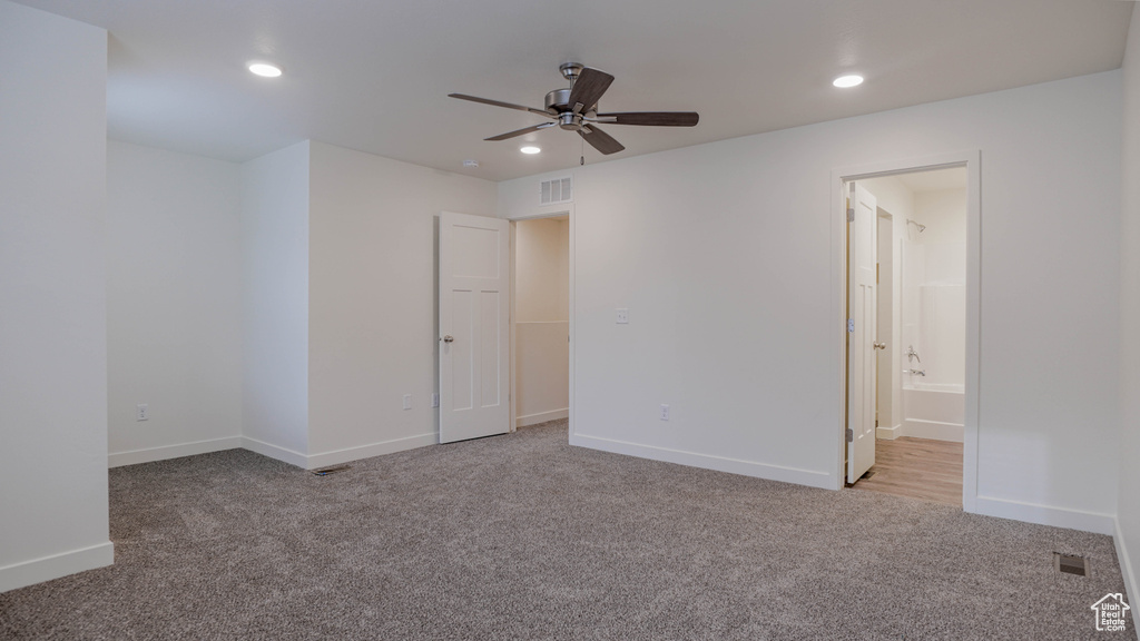 Unfurnished bedroom with connected bathroom, ceiling fan, and light carpet