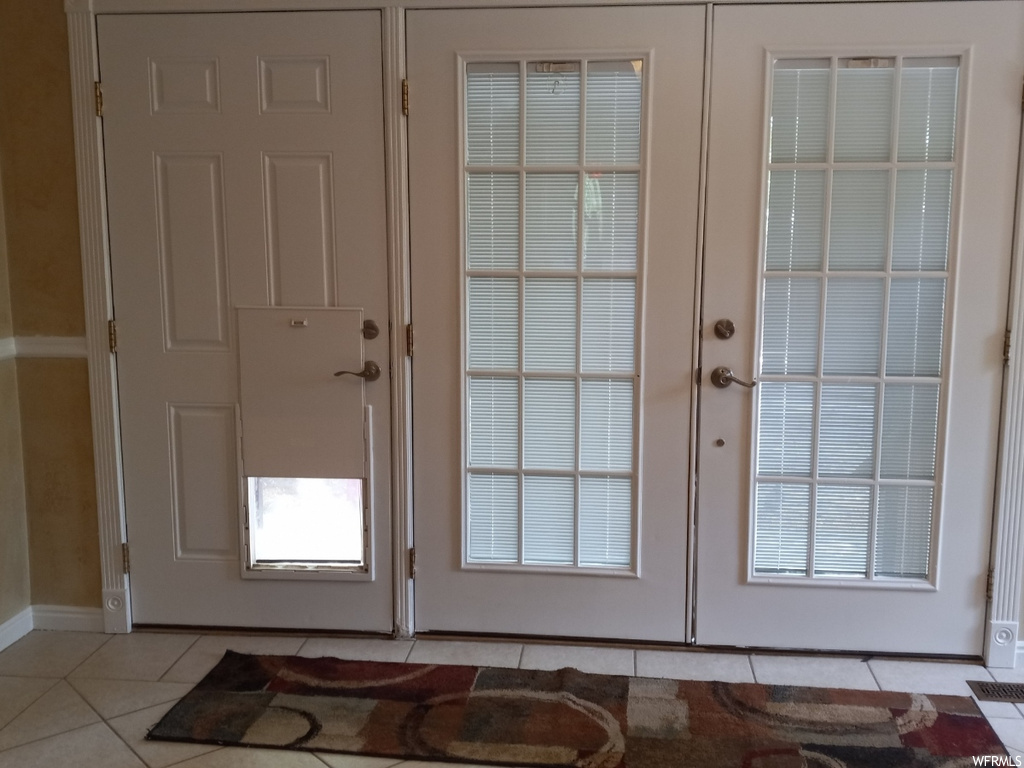 Doorway to outside with light tile flooring and french doors