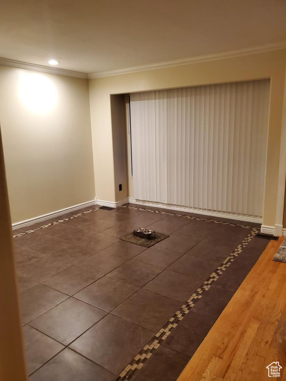 Empty room with crown molding and dark tile flooring
