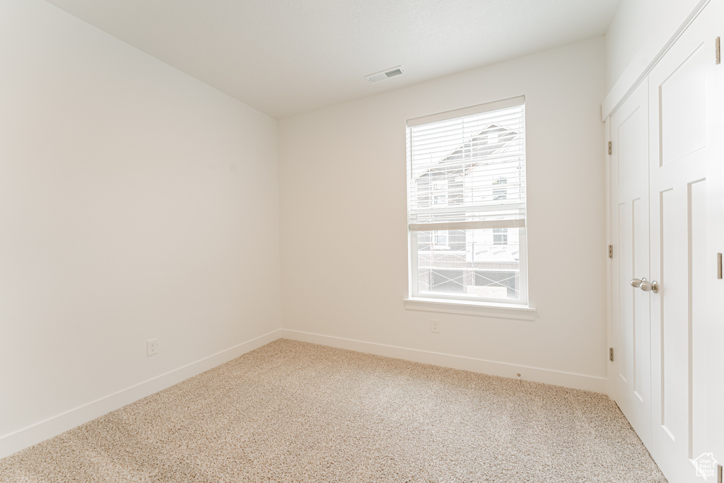 Unfurnished bedroom with a closet, carpet floors, and multiple windows