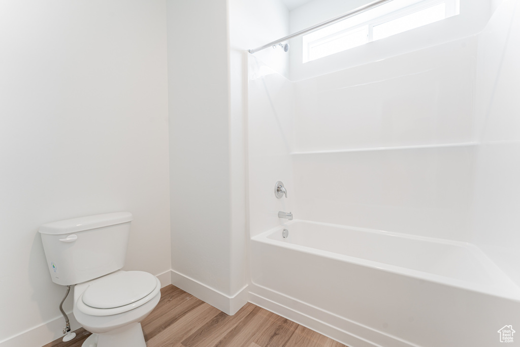 Bathroom featuring hardwood / wood-style flooring, toilet, and  shower combination
