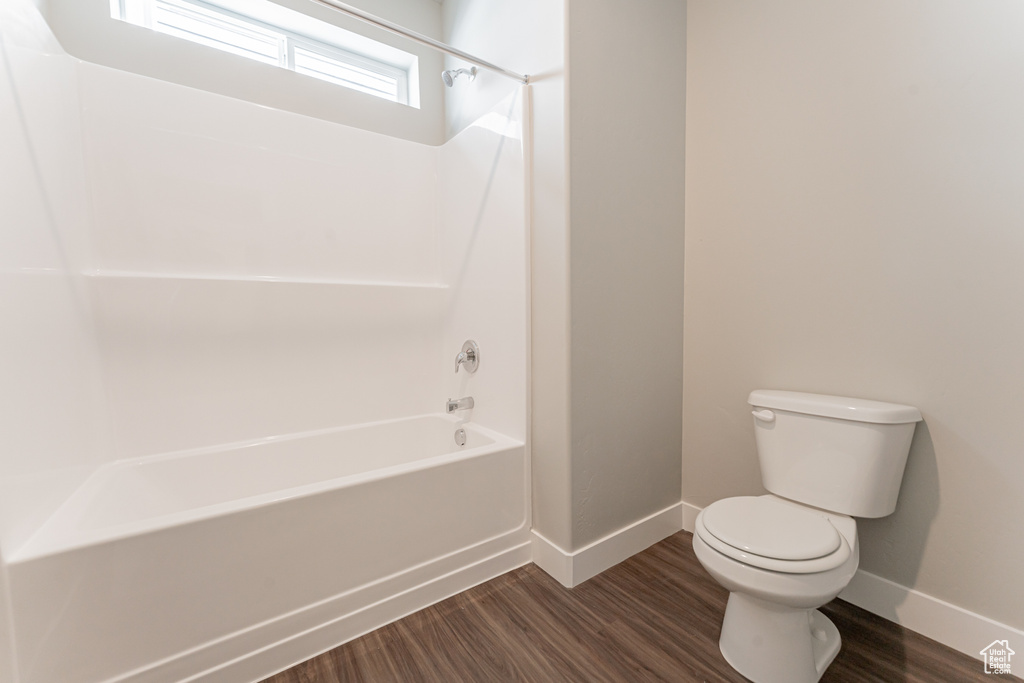 Bathroom featuring hardwood / wood-style floors, shower / bath combination, and toilet