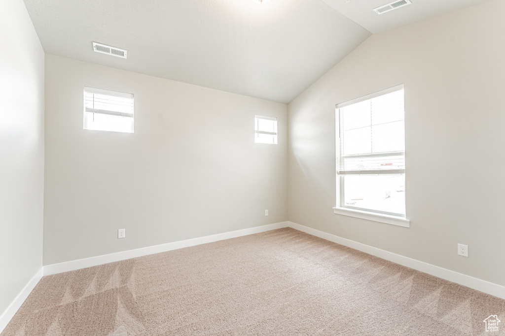Unfurnished room featuring vaulted ceiling and carpet floors