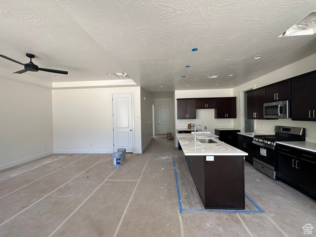 Kitchen with stainless steel appliances, a kitchen island with sink, a breakfast bar area, sink, and ceiling fan