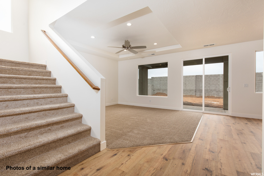 Staircase featuring light hardwood / wood-style flooring, ceiling fan, and a raised ceiling