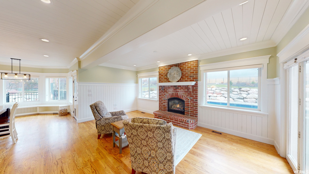 Living room featuring light hardwood / wood-style flooring, a brick fireplace, a wealth of natural light, and brick wall