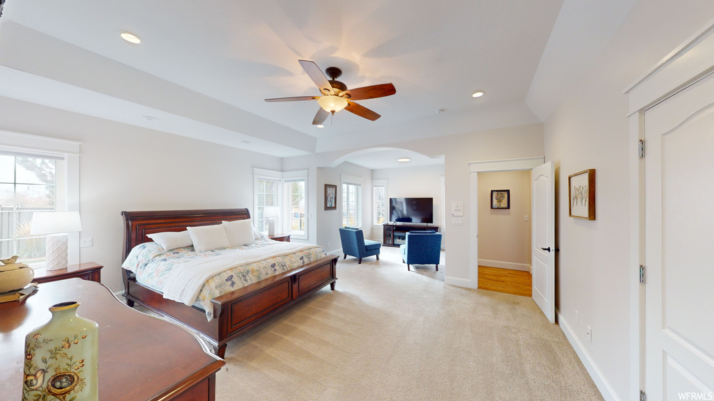 Bedroom featuring light colored carpet, ceiling fan, and multiple windows