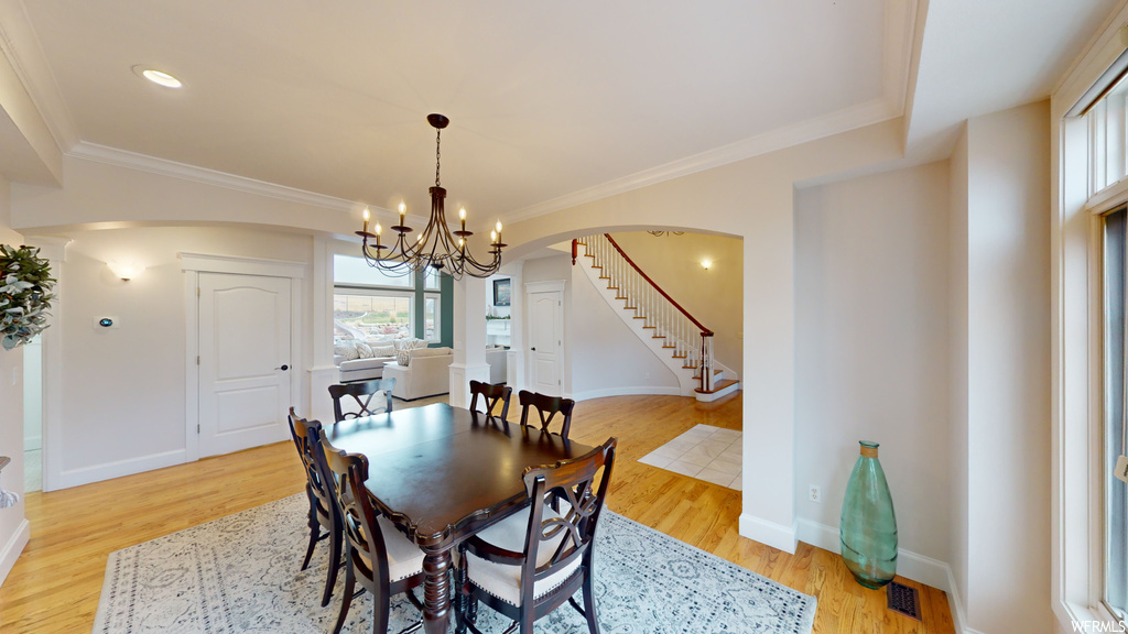 Dining space with ornamental molding, a notable chandelier, and light hardwood / wood-style floors