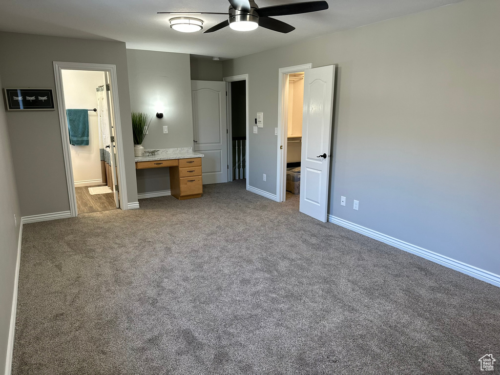 Unfurnished bedroom with ensuite bathroom, carpet, and ceiling fan