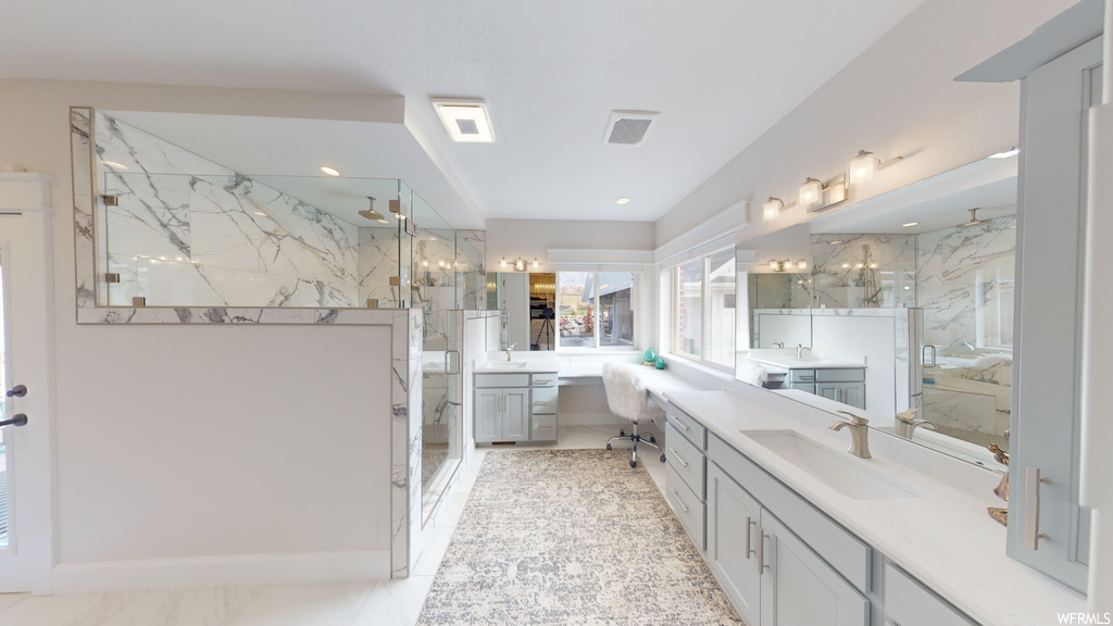 Bathroom featuring tile floors, a shower with door, and vanity with extensive cabinet space