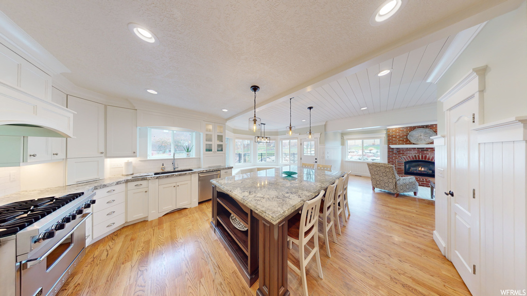 Kitchen featuring a center island, light hardwood / wood-style floors, stainless steel appliances, and white cabinetry