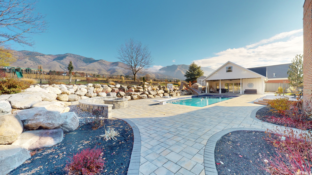 View of pool featuring a jacuzzi, a patio, and a mountain view