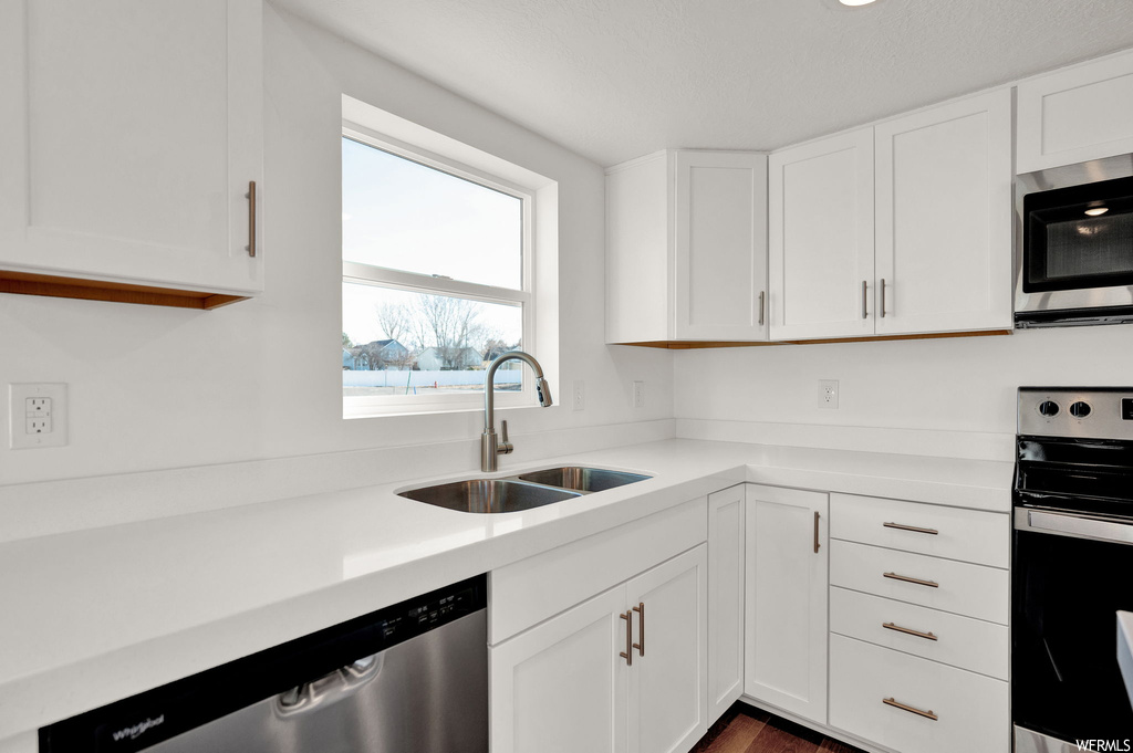 Kitchen with white cabinets, sink, dark wood-type flooring, and stainless steel appliances