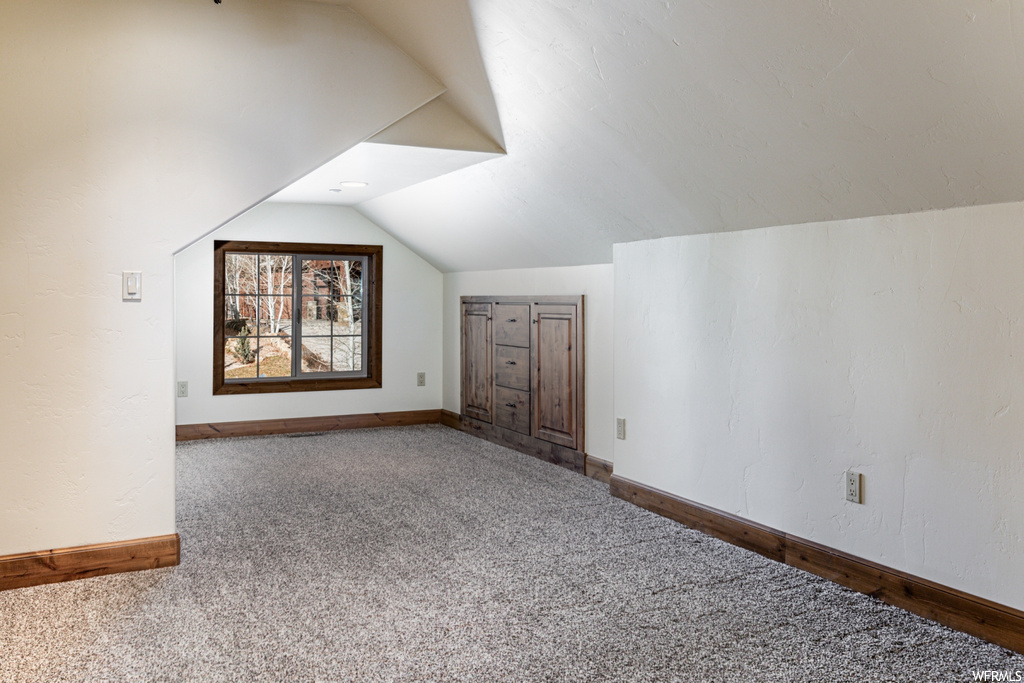 Additional living space with lofted ceiling and carpet flooring
