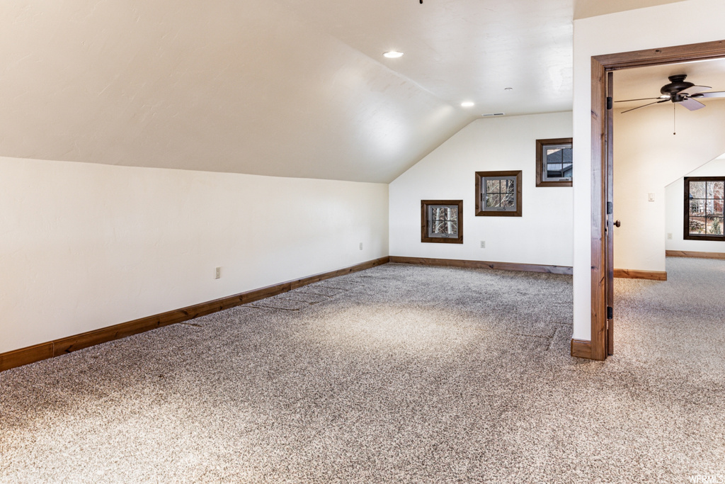 Additional living space featuring lofted ceiling, ceiling fan, and light carpet