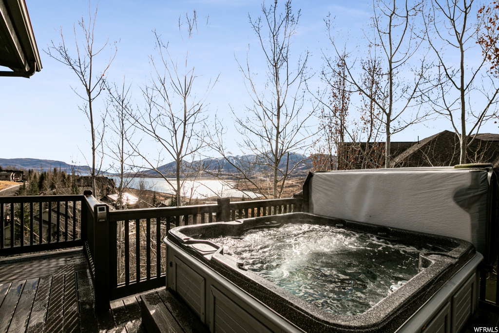 Snow covered deck featuring a hot tub and a mountain view