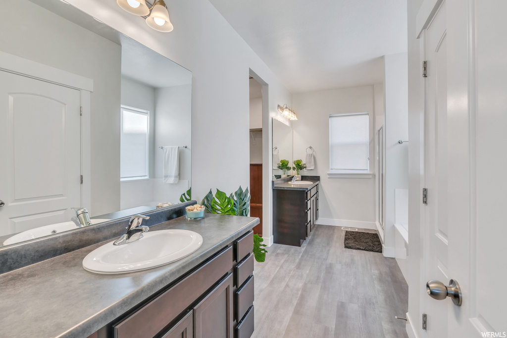 Bathroom featuring dual sinks, oversized vanity, and hardwood / wood-style floors