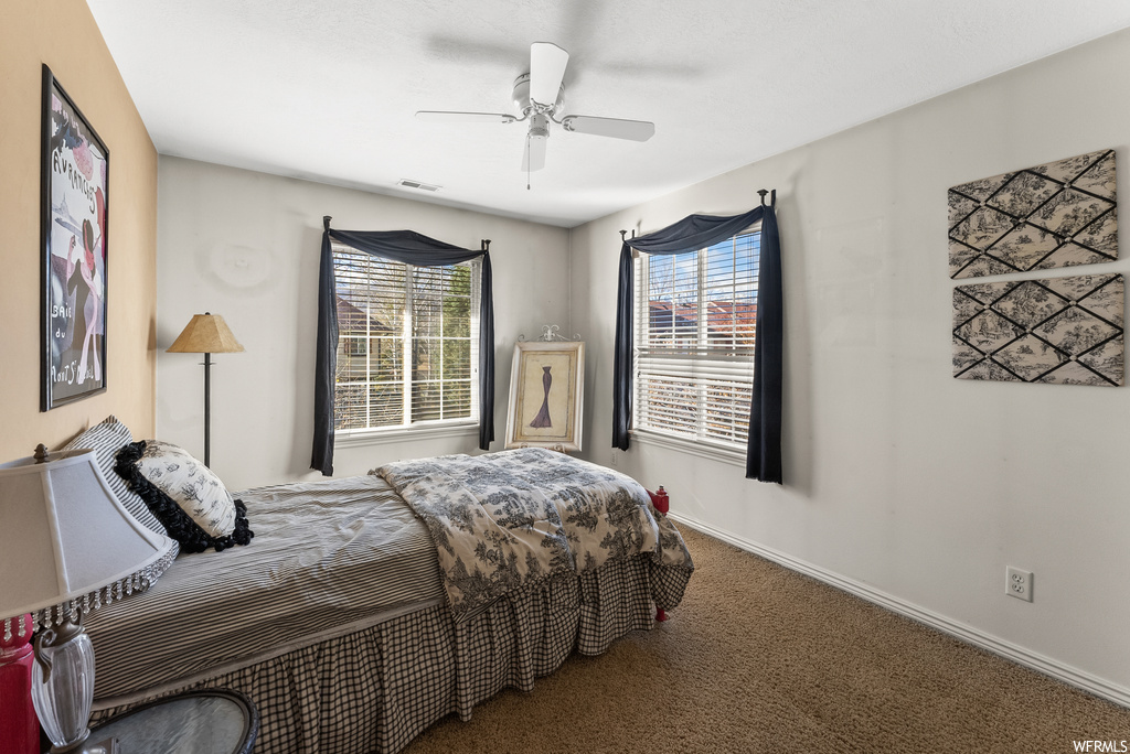 Bedroom featuring dark carpet, ceiling fan, and multiple windows