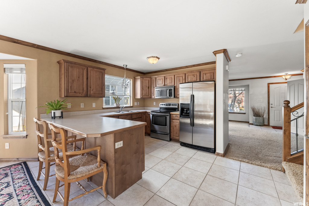 Kitchen featuring a breakfast bar, a wealth of natural light, stainless steel appliances, and kitchen peninsula