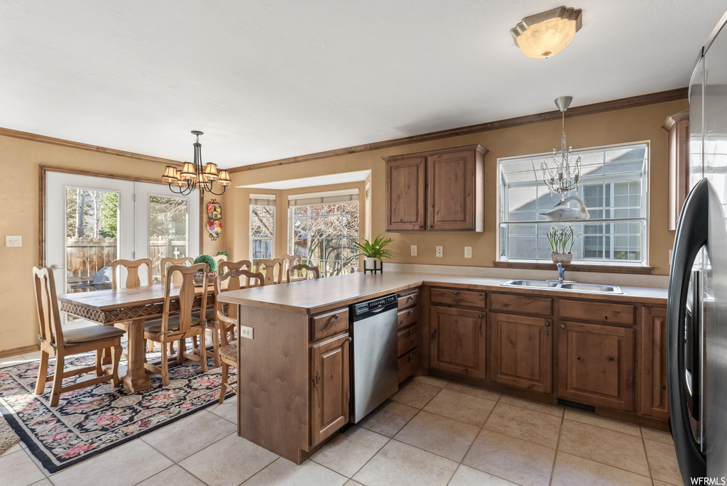 Kitchen featuring hanging light fixtures, dishwasher, a notable chandelier, light tile floors, and kitchen peninsula