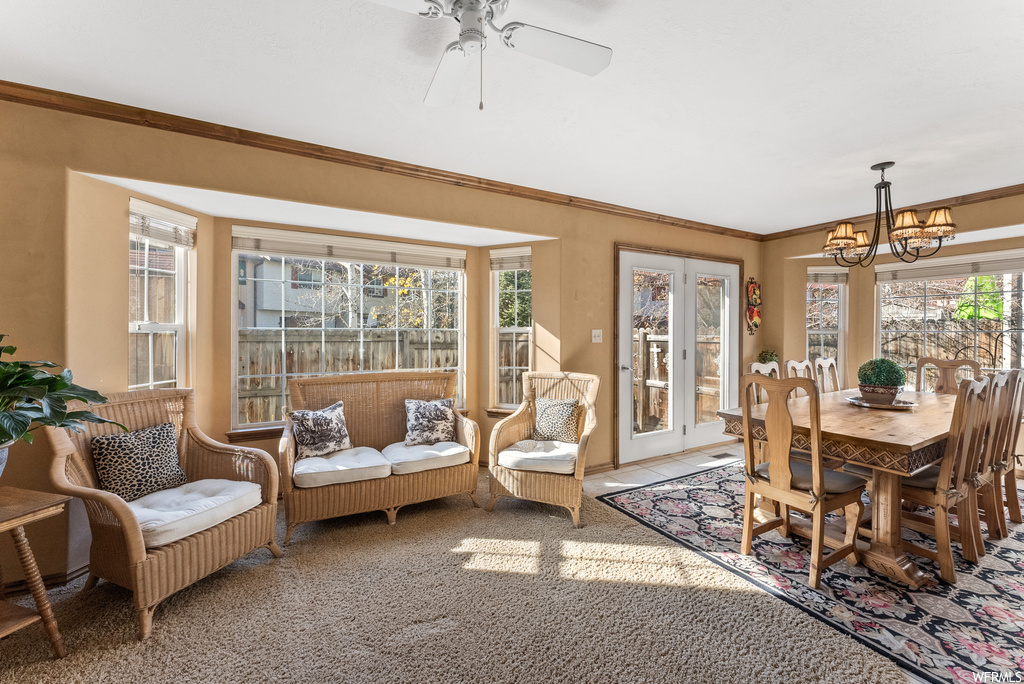 Sunroom featuring ceiling fan with notable chandelier