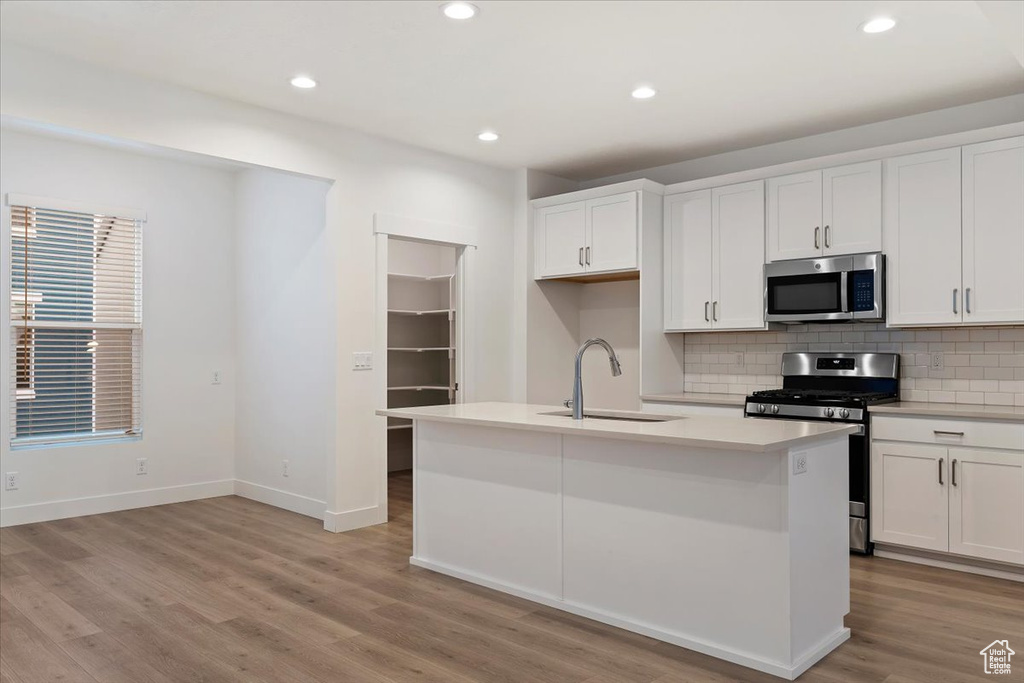 Kitchen featuring sink, stainless steel appliances, white cabinets, and light hardwood / wood-style flooring