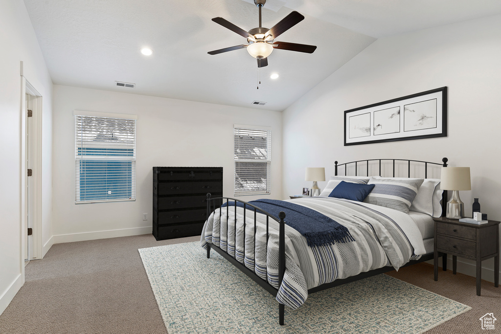 Bedroom with multiple windows, vaulted ceiling, ceiling fan, and light colored carpet