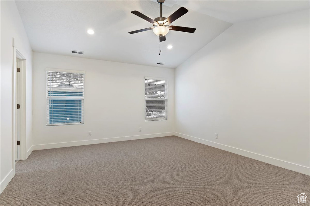 Spare room with vaulted ceiling, light carpet, and ceiling fan