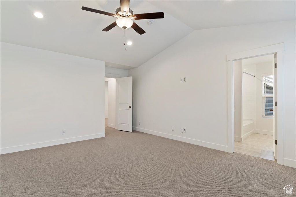 Empty room featuring vaulted ceiling, light colored carpet, and ceiling fan
