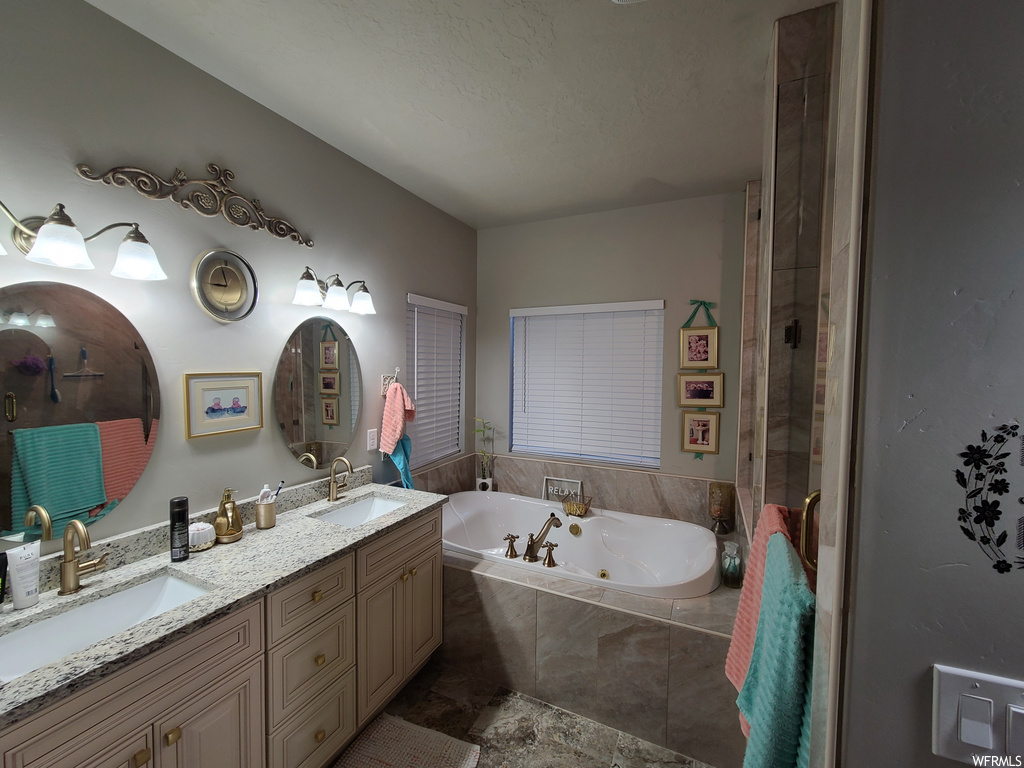 Bathroom featuring dual sinks, independent shower and bath, and vanity with extensive cabinet space