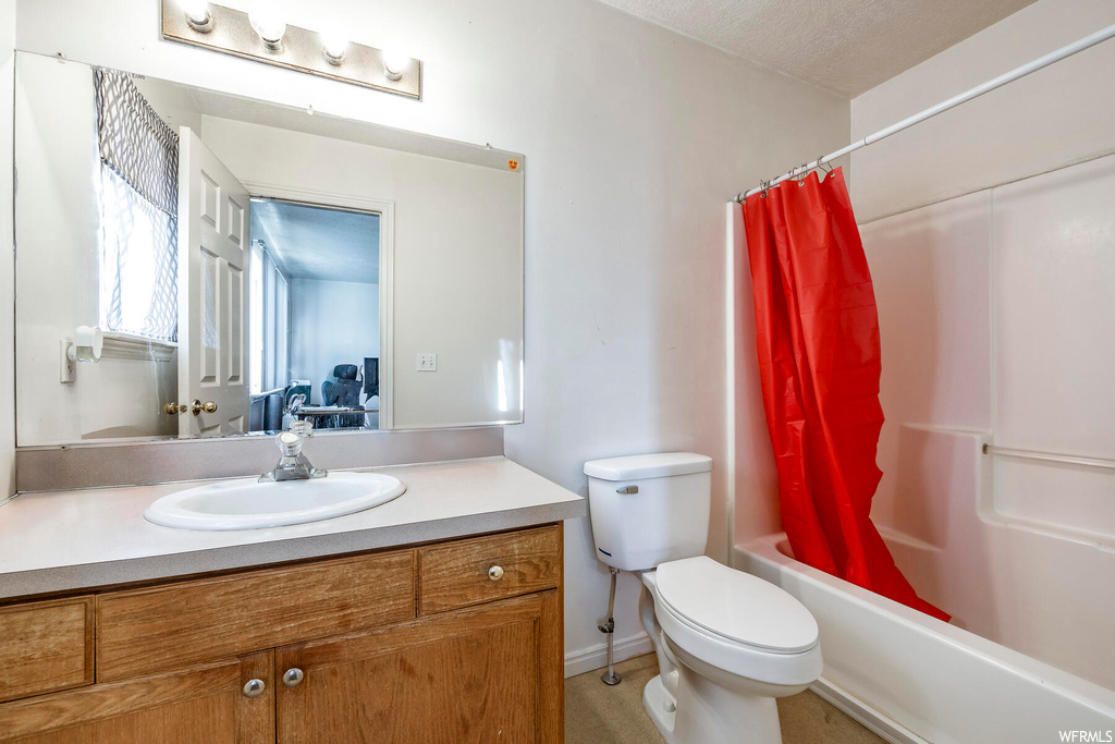 Full bathroom with a textured ceiling, vanity, toilet, and shower / tub combo with curtain
